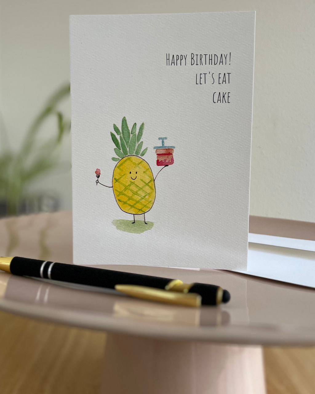 Birthday card with a pineapple illustration on a cake stand.