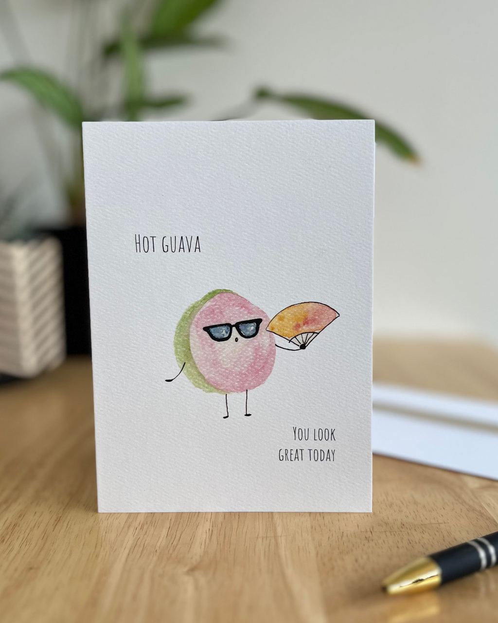 Greeting card with cartoon guava characters on a wooden surface