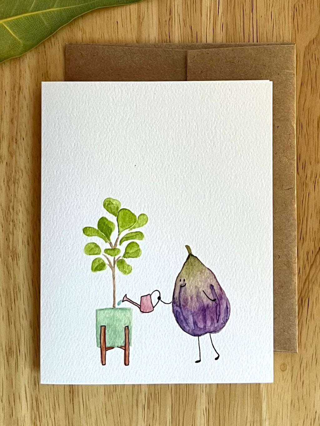 A clever visual pun for plant lovers! Watercolor fig fruit watering a potted fiddleleaf fig. A unique, text-free card for botanical enthusiasts.