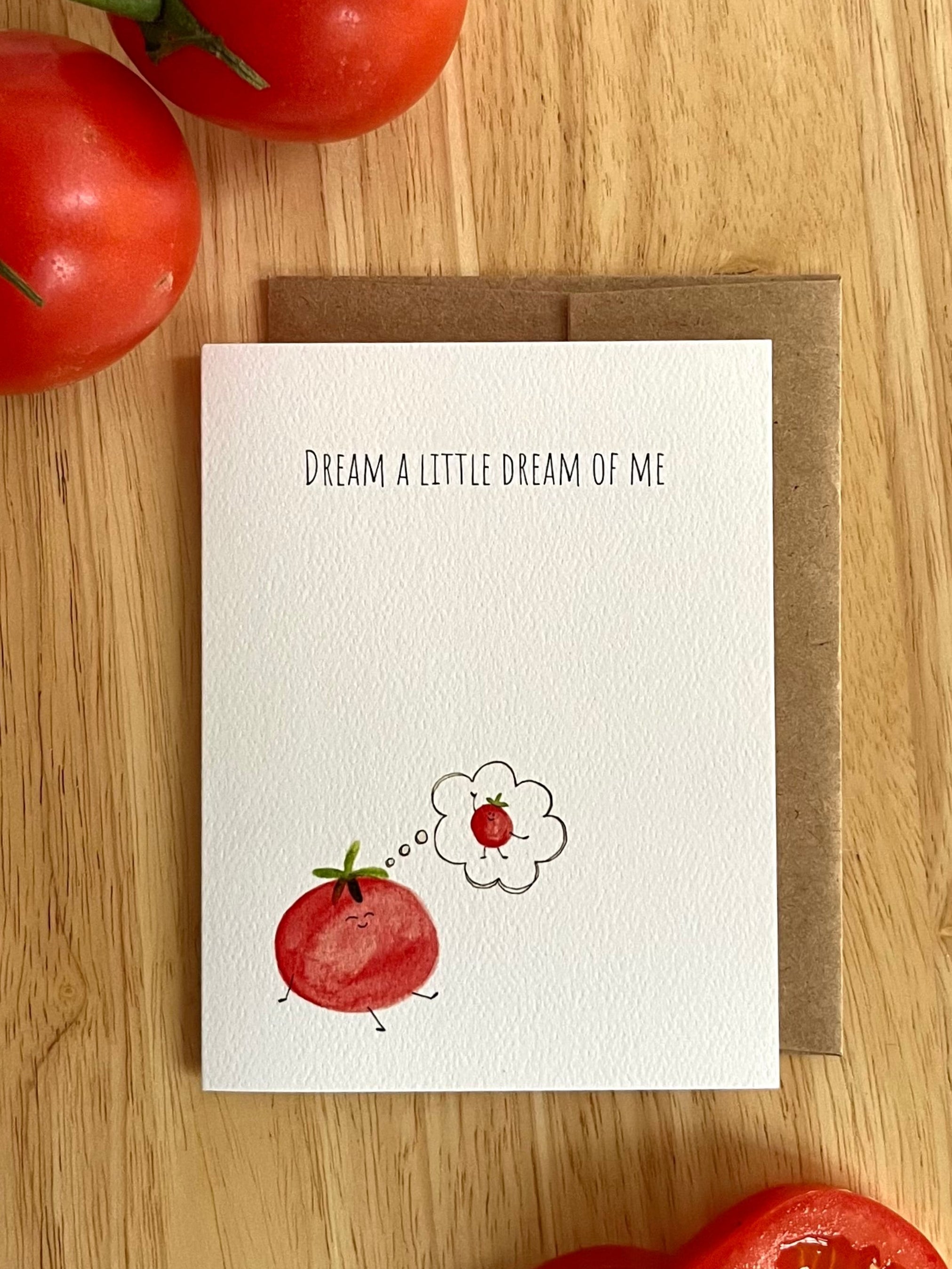 Mei Pie Studio Greeting card with tomato illustration and text 'Dream a little dream of me' on a wooden surface with tomatoes.