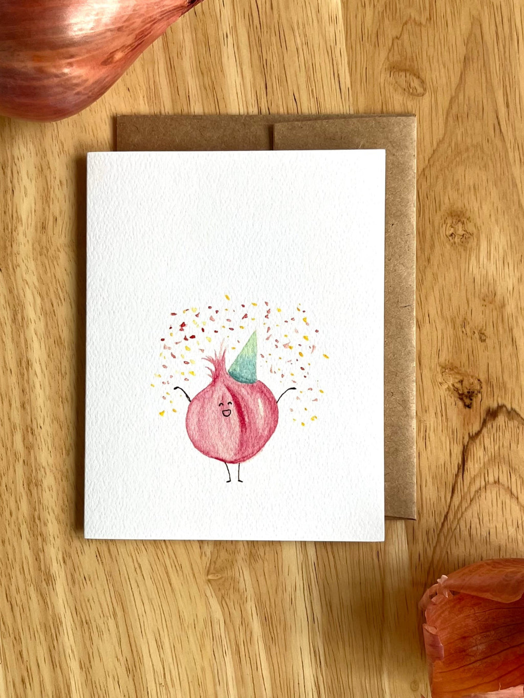 Mei Pie Studio Celebration Card with a cartoon funion onion character on a wooden surface with real onions.