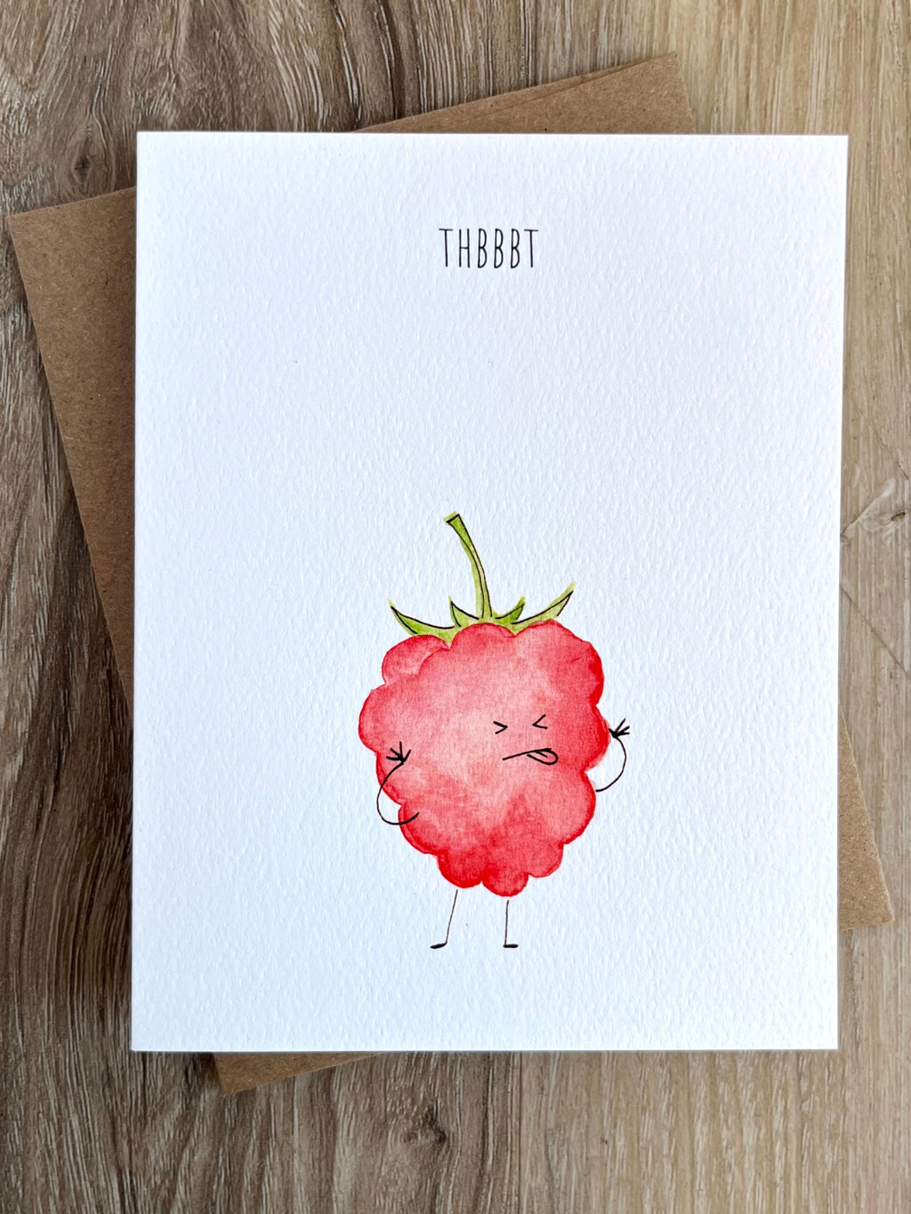 Greeting card with a cartoon raspberry character on a wooden surface