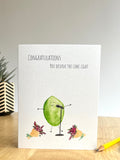 Greeting card with a green  lime character and Congratulations you deserve the limelight text. Card on a wooden surface