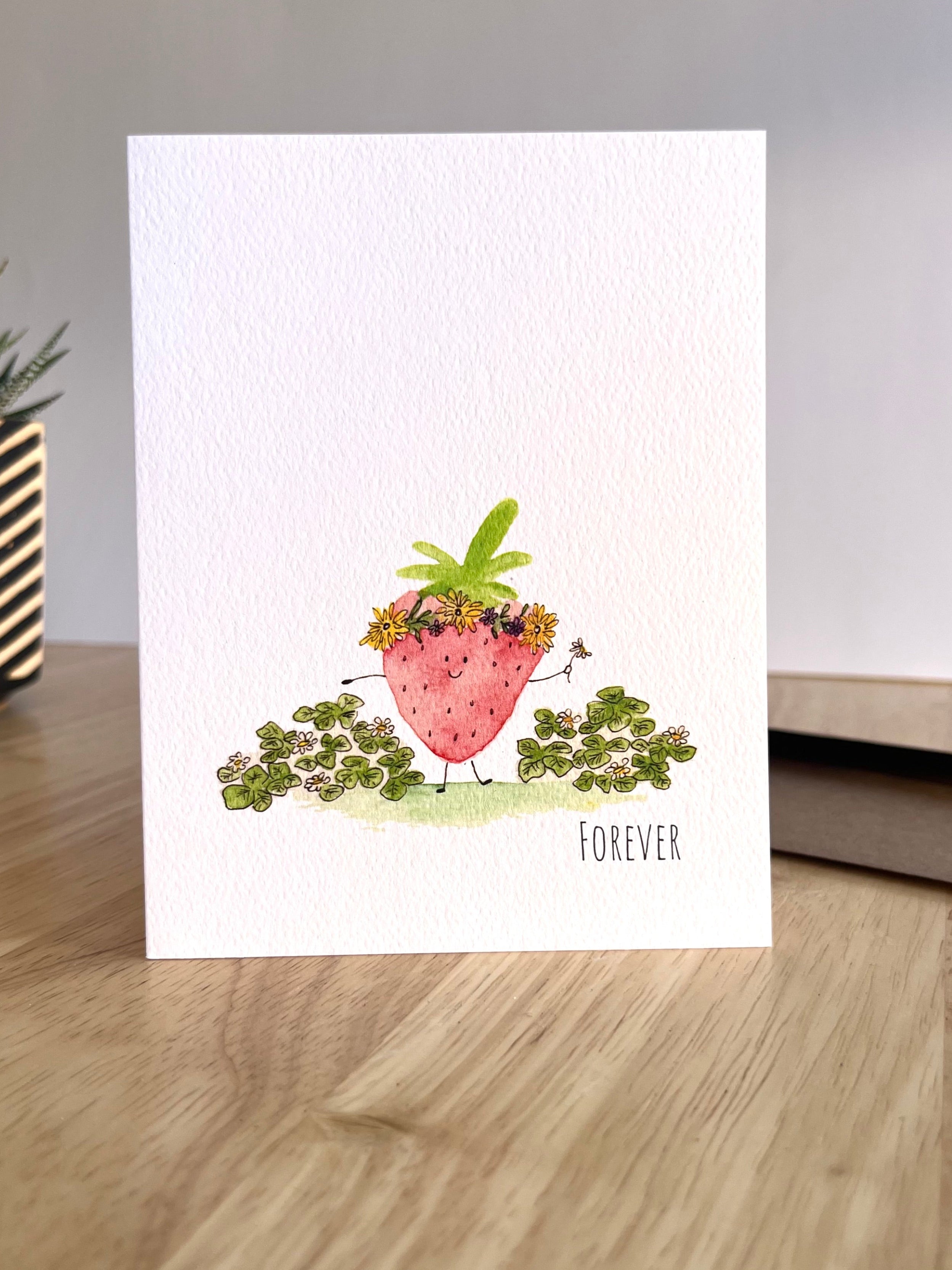 Greeting card with strawberry illustration on a wooden surface