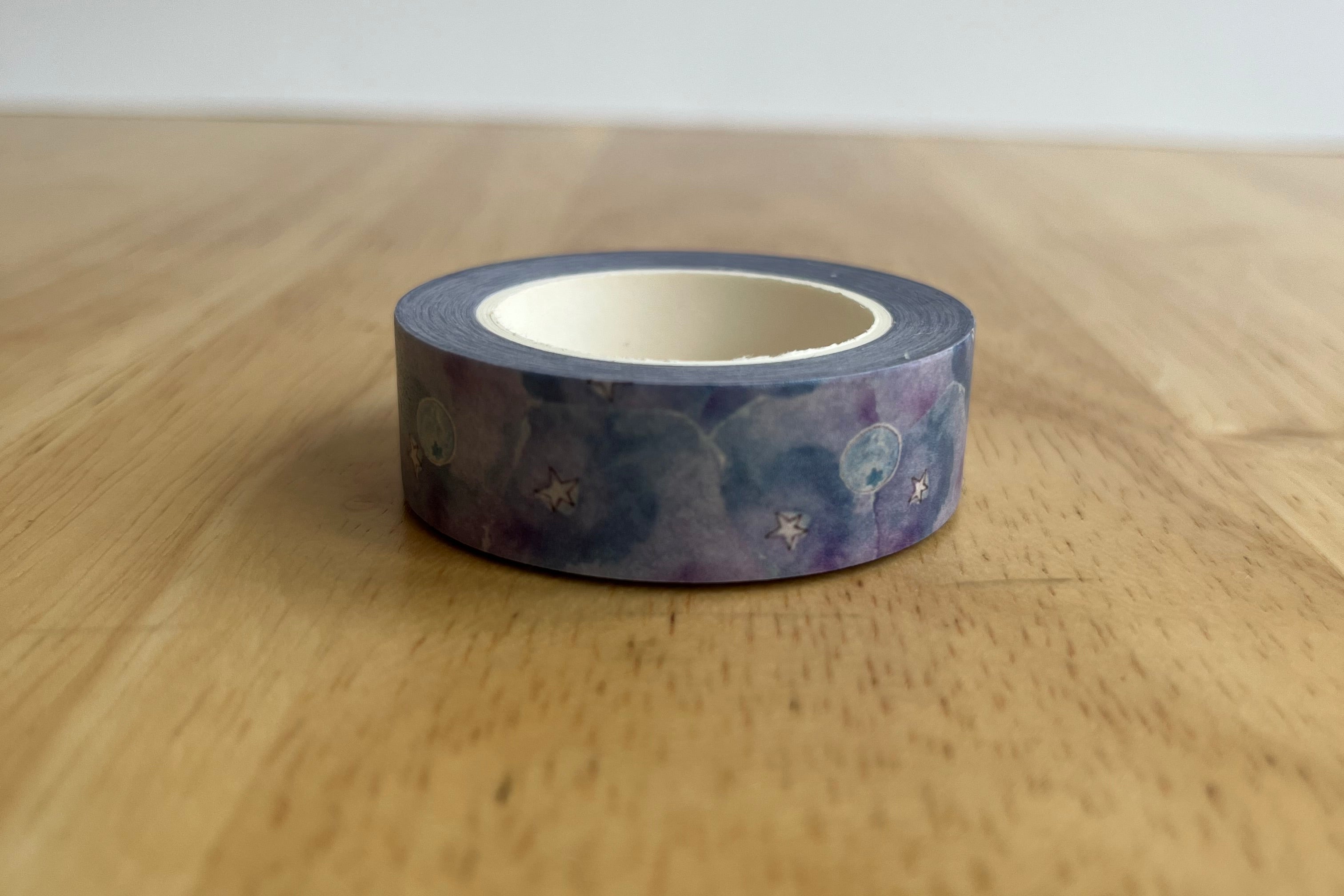 Roll of decorative tape with a space-themed design on a wooden surface