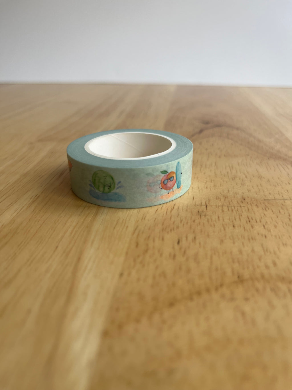 Roll of decorative tape with cartoon designs on a wooden surface