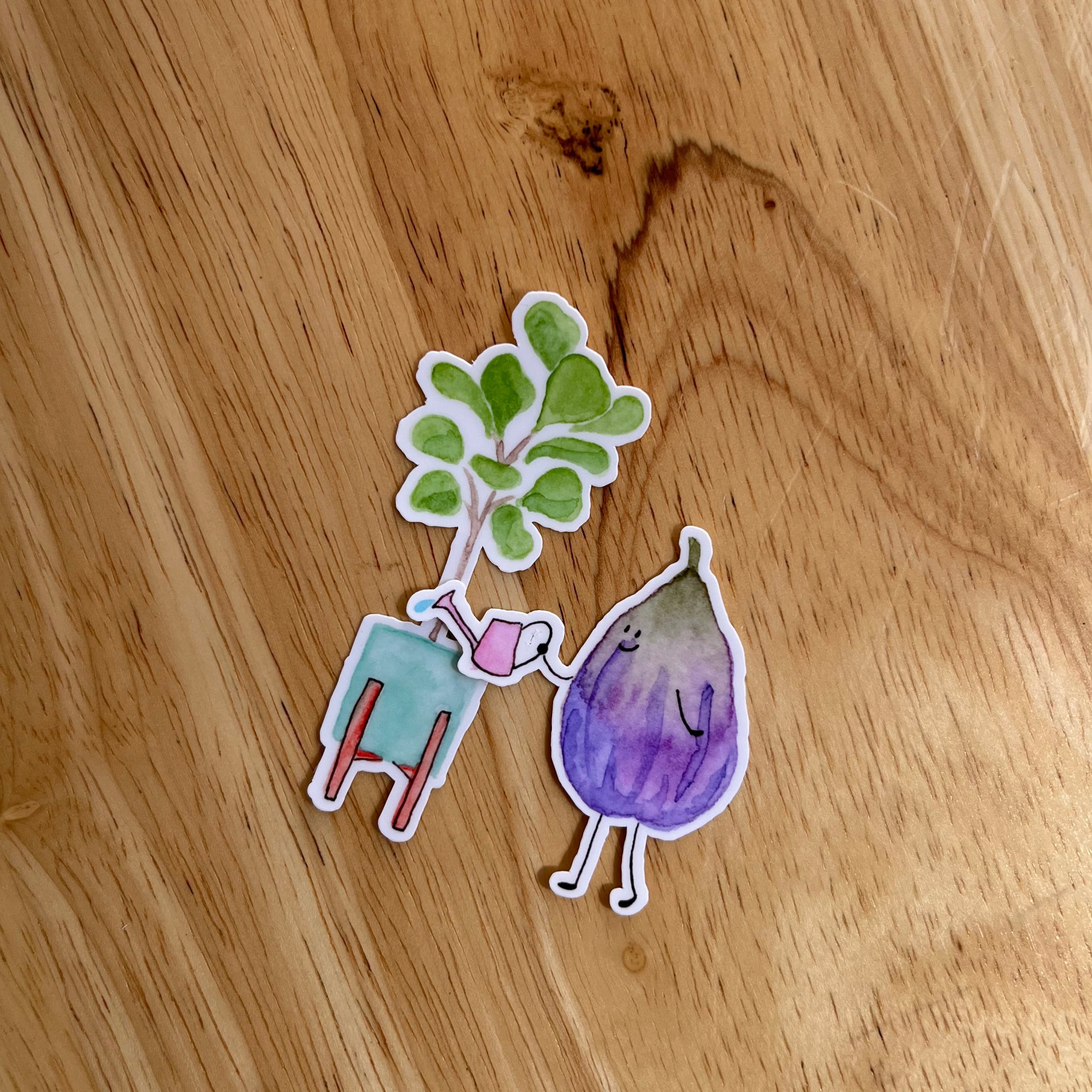 Two stickers on a wooden surface, one resembling a plant and the other an fig