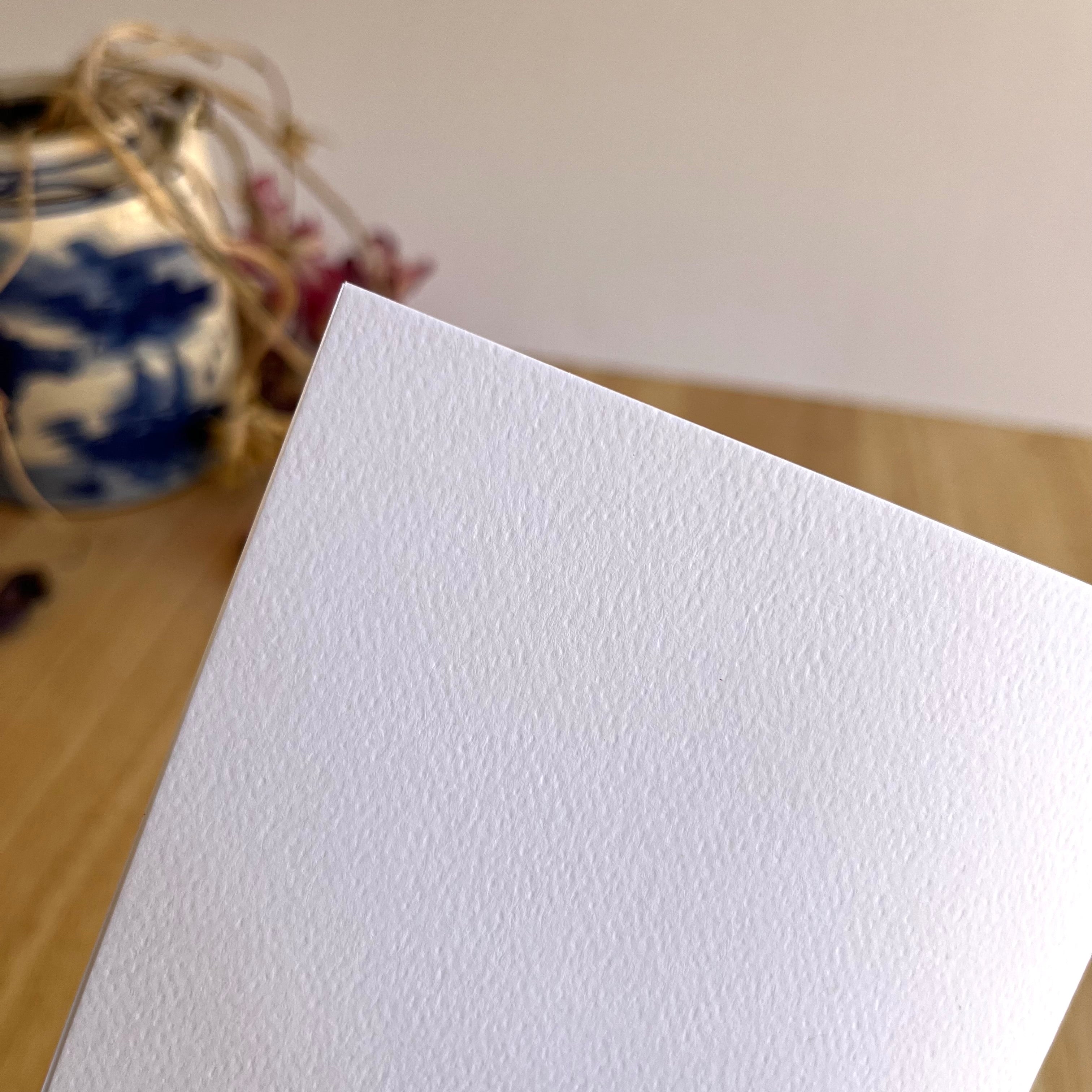 White textured paper on a wooden surface with a blurred background
