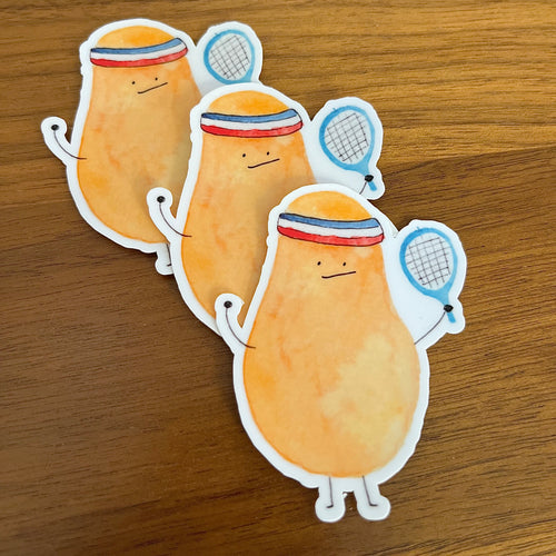 Three cartoon potato-shaped stickers with tennis rackets and headbands arranged on a wooden surface.