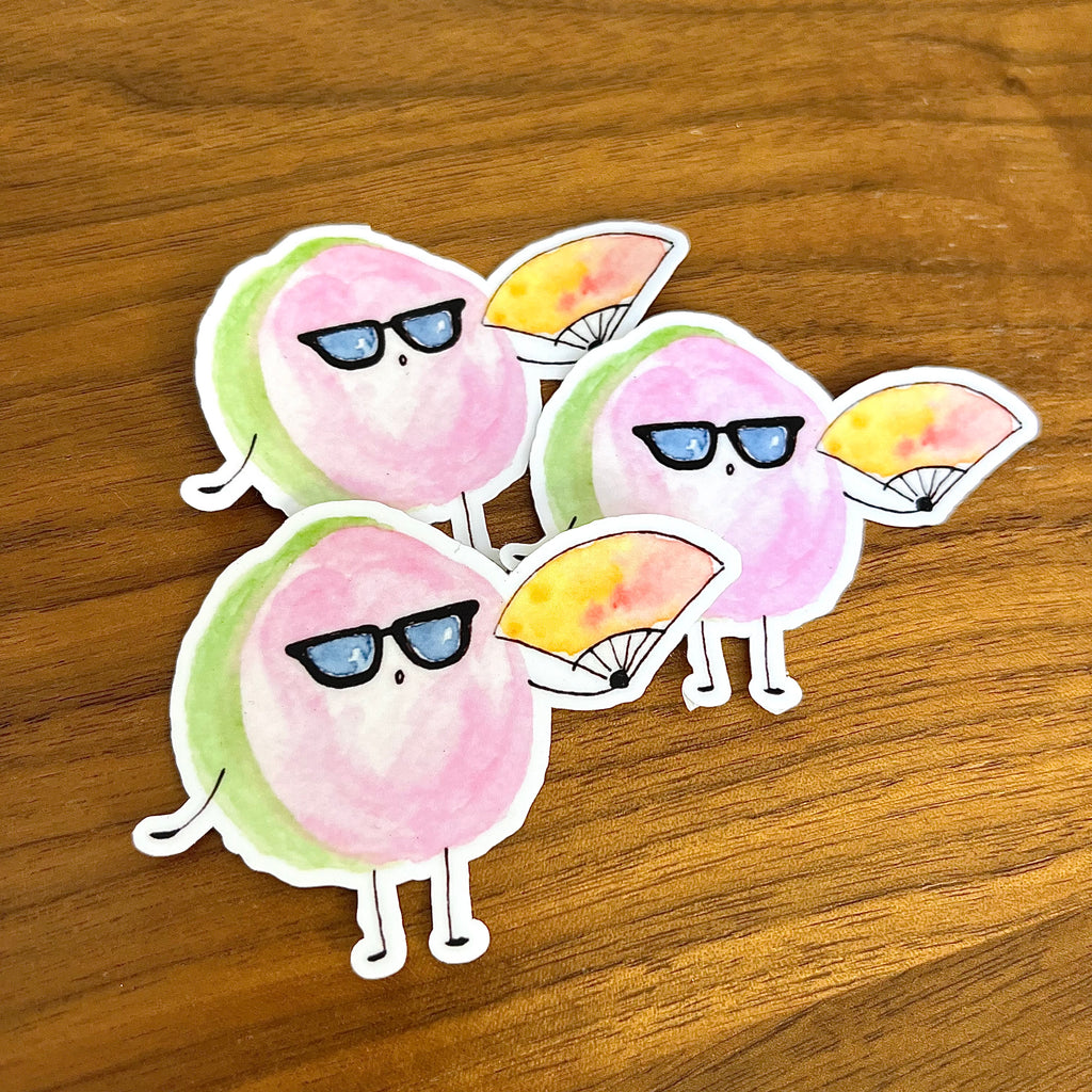 Three cartoon avocado stickers with sunglasses and fans, arranged on a wooden surface.