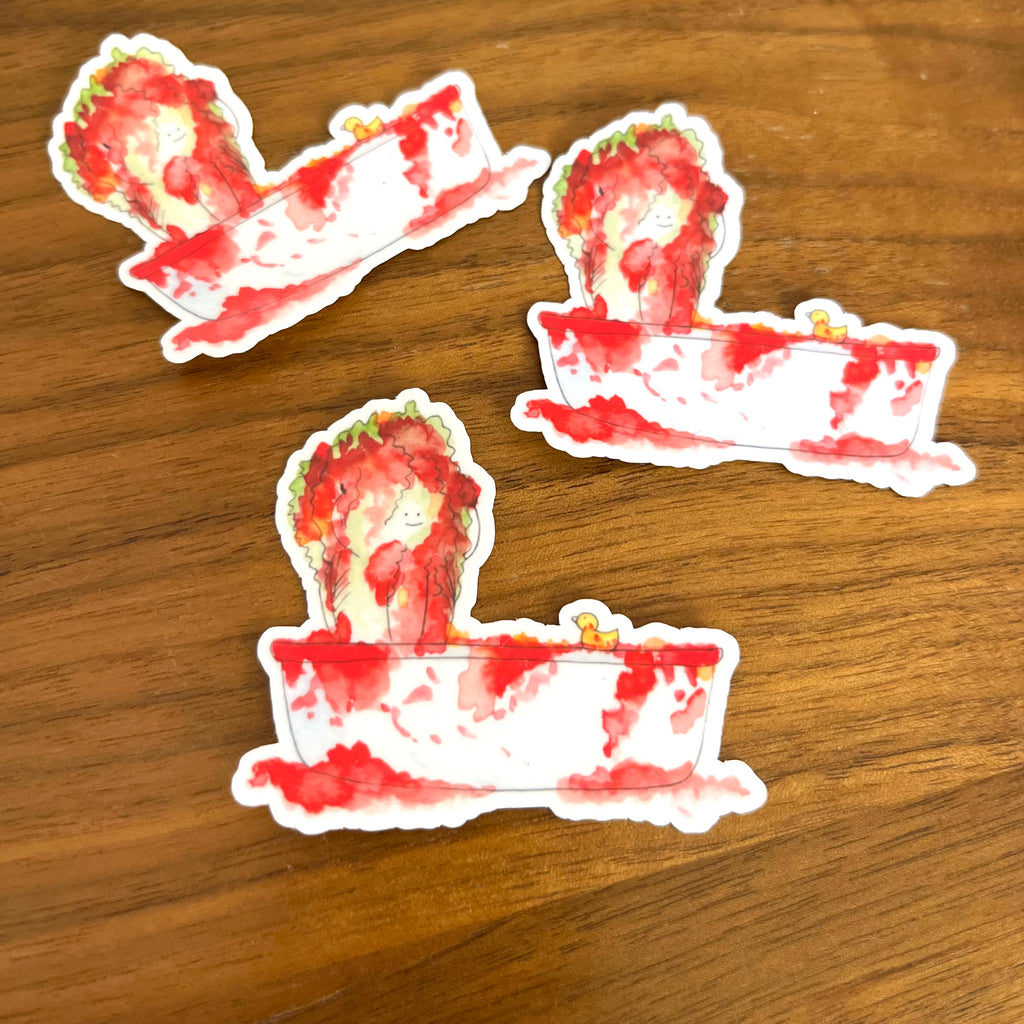 Three die-cut stickers featuring a watercolor illustration of a strawberry bathhouse scene, displayed on a wooden surface