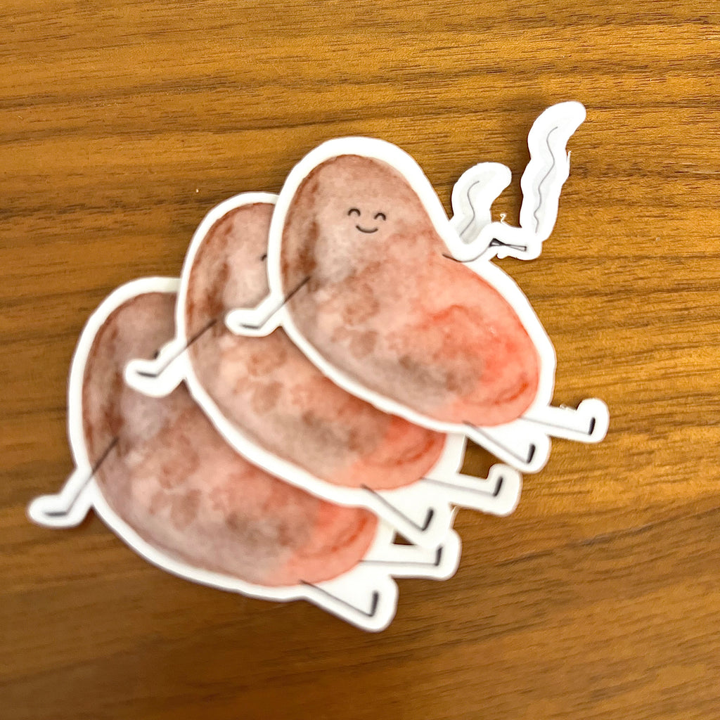 Three cartoon potato stickers with a smiling face and steam detail, arranged on a wooden surface