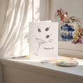 Greeting card with a martini glass and olives design on a white surface with art supplies.