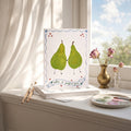 Two pears holding hands with a banner below on a windowsill with art supplies.