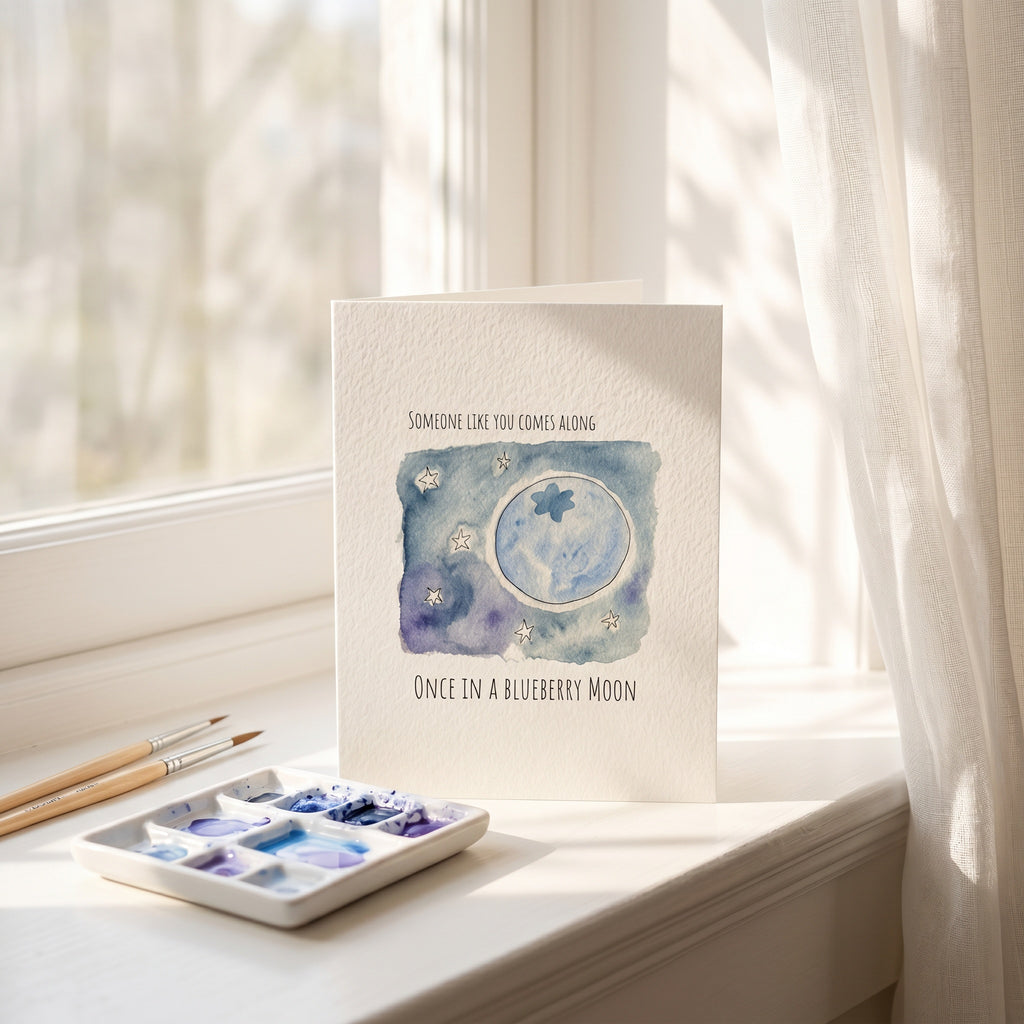 Card with watercolor design of a moon and stars on a windowsill with art supplies.
