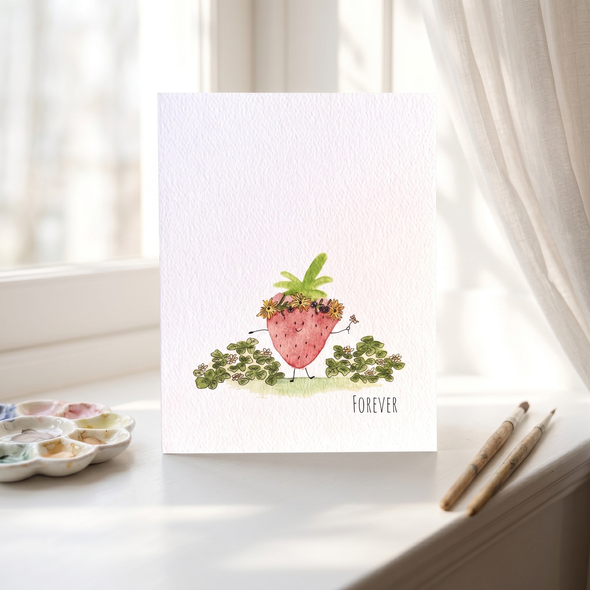 Card with strawberry illustration and 'Forever' text on a white surface with art supplies.