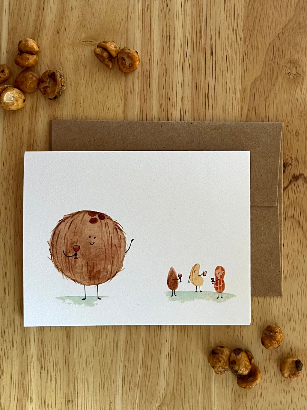 Horizontal watercolor card showing a large coconut waving to a group of smaller nuts holding drinks, depicting a relatable social situation.