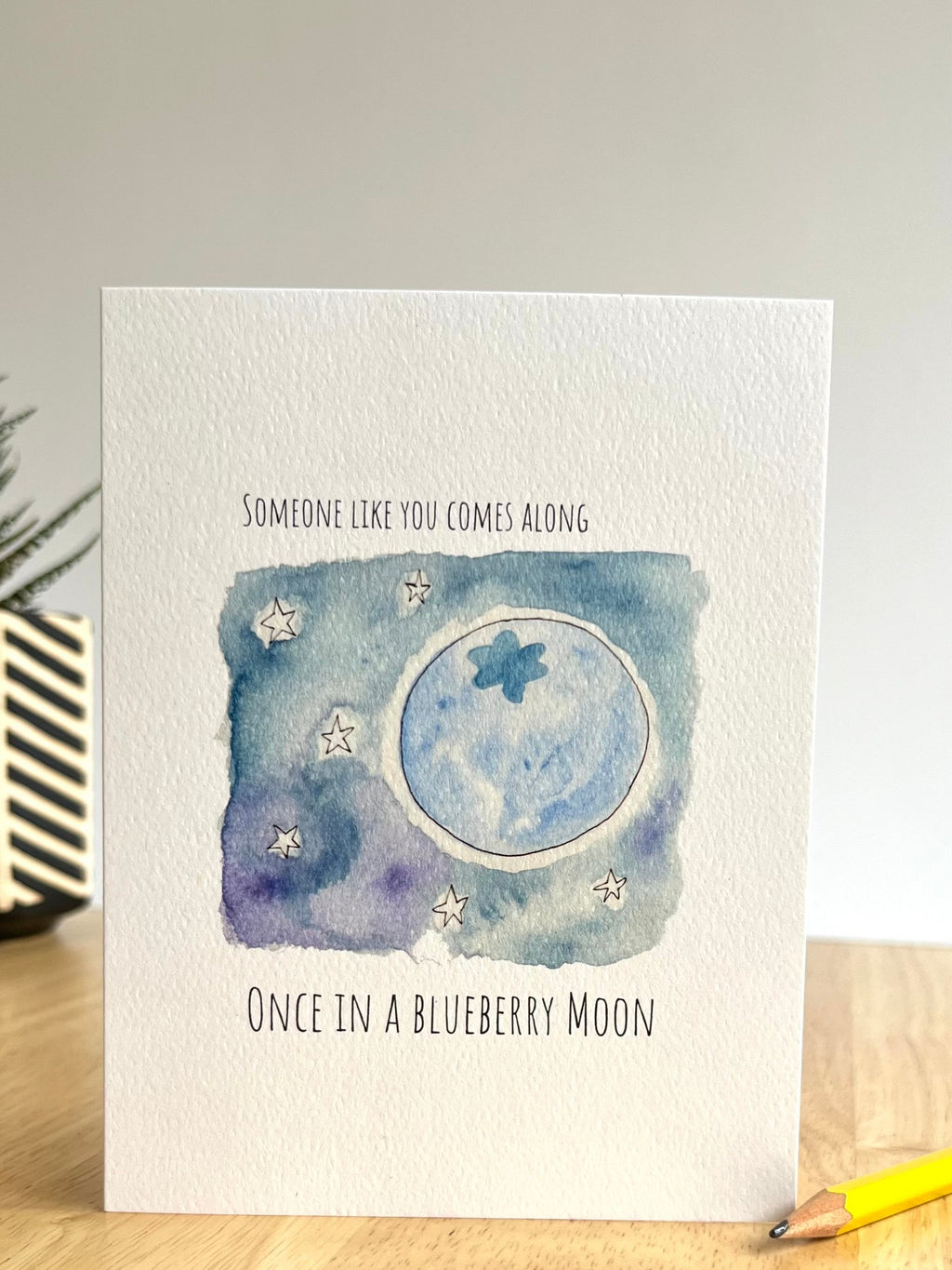 Greeting card with moon and star design on a wooden surface