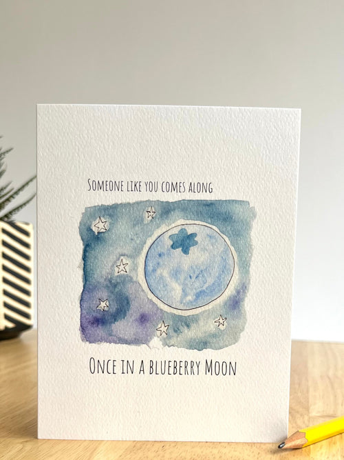 Greeting card with moon and star design on a wooden surface