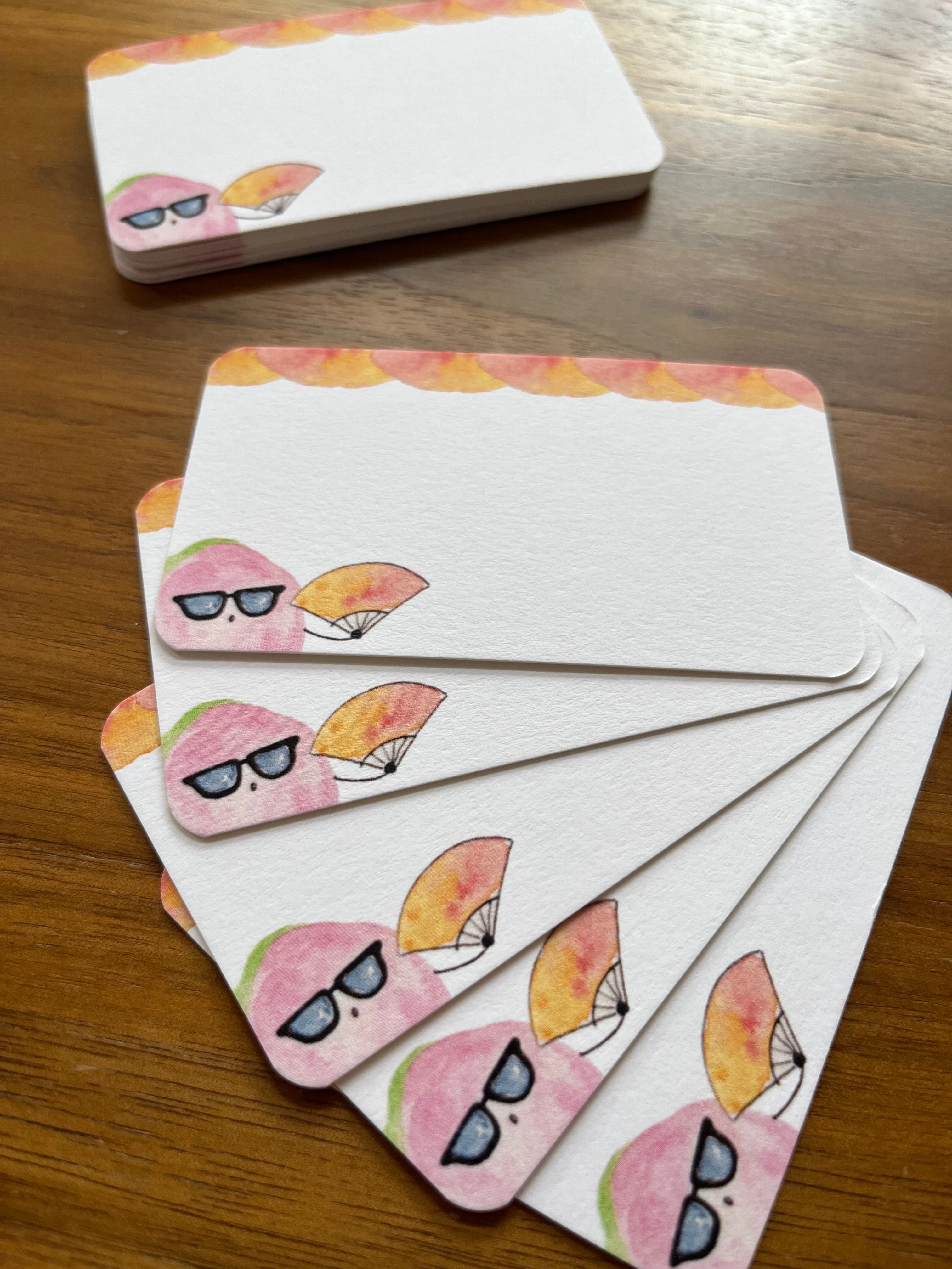 mei pie studio sassy pink guava mini note set holding a watercolor fan on classic crest neenah stock. close up on a wooden table