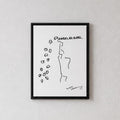 A minimalist black and white art print with a thin black frame, hanging on a textured light gray wall above a light wood console table with a ceramic vase.
